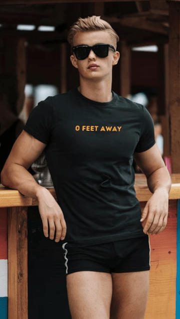 Model wearing 0 Feet Away Shirt – Funny Gay Grindr Gay Pride Tee, casual gay shirt with bold typography.