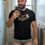 muscular bearded man taking a mirror selfie wearing a black QRLY Merch ‘Got Brotein’ t-shirt in a bathroom