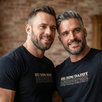 “gay couple smiling while wearing matching QRLY Merch ‘His Man Daddy’ shirts.