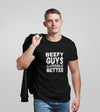 Model wearing a black shirt featuring 'Beefy Guys Cuddle Better' text, showcasing gay pride apparel.