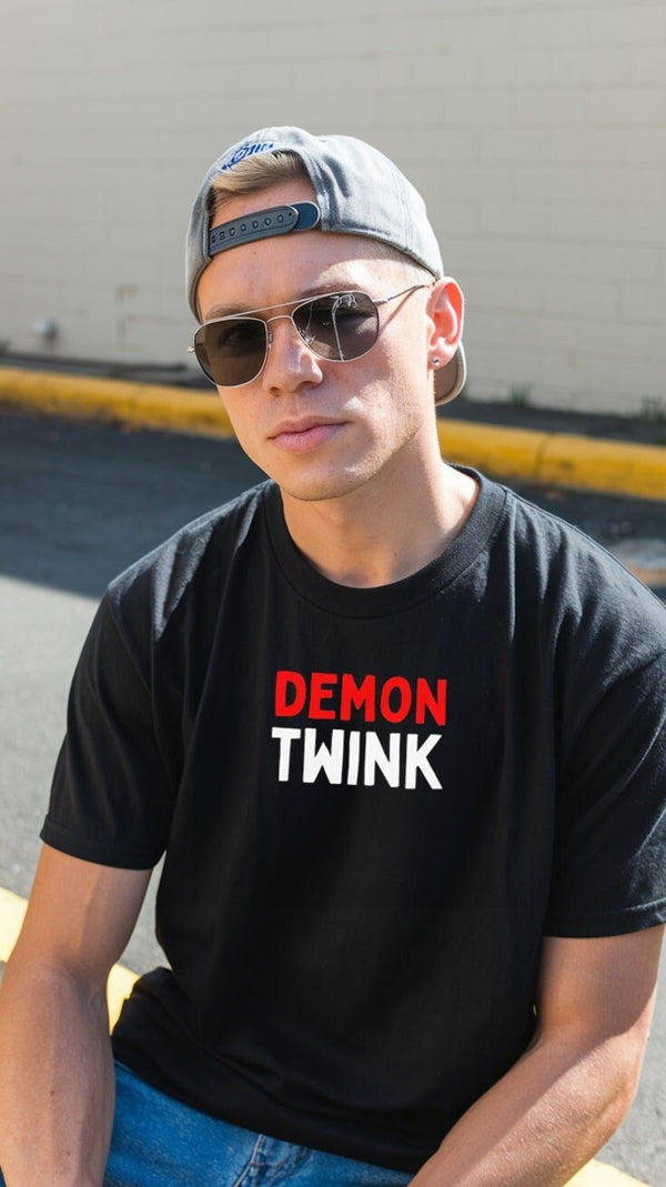 Young man wearing black t-shirt with 'Demon Twink Funny Gay Pride Tee' design.