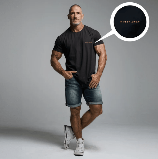 Man wearing a funny raunchy gay embroidered tee and denim shorts, showcasing gay pride apparel.