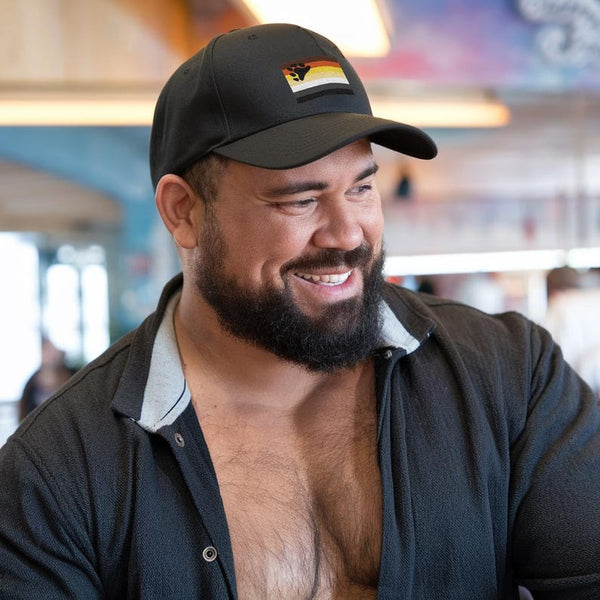 Smiling man wearing Gay Pride Bear Bear Paw Hat with rainbow flag design.