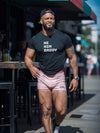 He/Him Daddy Shirt Gay Bear Pride T-Shirt for Men LGBTQ+ Queer Apparel, muscular man wearing black tee and pink shorts.