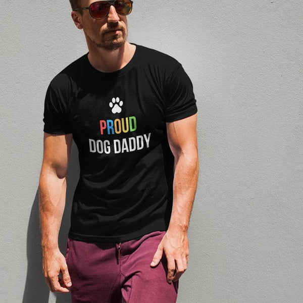 Man wearing Proud Gay Dog Dad Shirt in black, showcasing LGBT pride design and paw print.