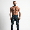 Muscular man wearing Cyber Bones Men’s Leggings with neon skeleton design.