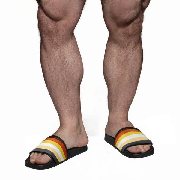 Man wearing Gay Bear Pride Slippers with vibrant rainbow stripes for summer activities.