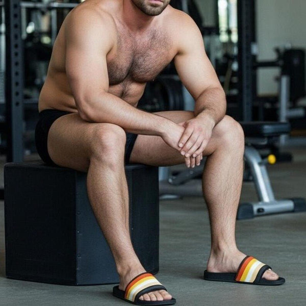 Man wearing open-toed Gay Bear Pride Slippers in workout setting.