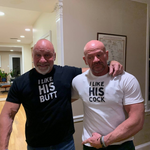 gay couple smiling indoors wearing matching QRLY Merch t-shirts with humorous relationship slogans.