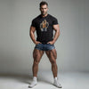 Muscular man in black gay pride shirt and denim shorts, showcasing vintage biker design.