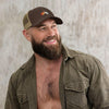 Subtle Gay Bear Pride Trucker Hat worn by a smiling bearded man, stylish design.